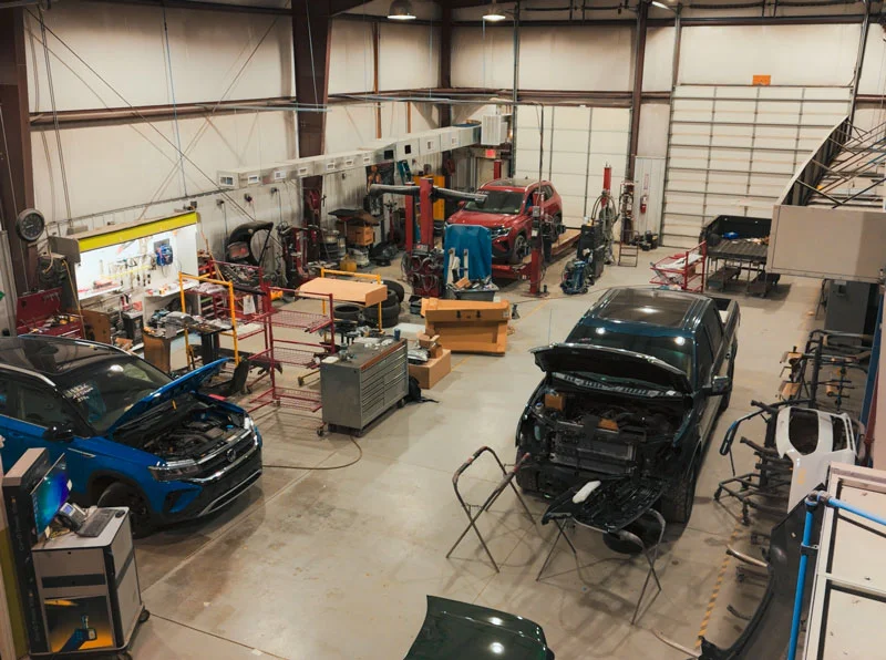 Wide image of garage with cars.